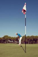 jogador de golfe acertando tiro em dia ensolarado foto