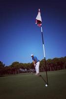 jogador de golfe acertando tiro em dia ensolarado foto