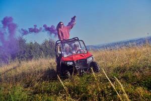 pessoas animadas se divertindo aproveitando um belo dia ensolarado segurando tochas coloridas enquanto dirigia um carro de buggy off road foto