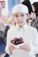 menino muçulmano segurando um prato cheio de datas doces foto