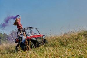 pessoas animadas se divertindo aproveitando um belo dia ensolarado segurando tochas coloridas enquanto dirigia um carro de buggy off road foto