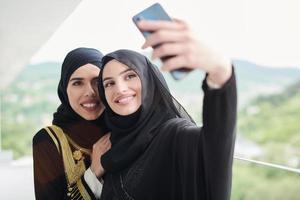 mulheres muçulmanas tirando foto de selfie na varanda