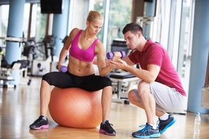 jovem mulher desportiva com levantamento de pesos de exercício de treinador foto