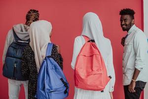 um grupo de estudantes muçulmanos africanos com mochilas posando em um fundo rosa. o conceito de educação escolar. foto