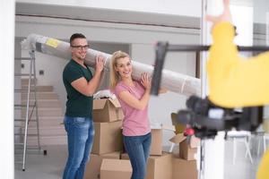 casal carregando um tapete se mudando para nova casa foto