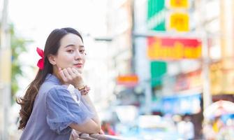 mulher bonita asiática no vestido qipao azul-cinza está de pé smilie feliz. cidade da china à beira da estrada, tema do ano novo chinês da tailândia foto