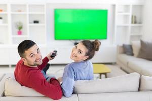 jovem casal no sofá assistindo televisão foto