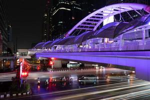 paisagem urbana de bangkok à noite com iluminação da passarela e veículos foto
