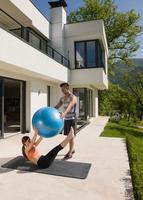 mulher e personal trainer fazendo exercício com bola de pilates foto