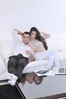 casal alegre relaxa e trabalha no computador portátil em casa moderna foto