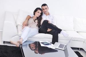 casal alegre relaxa e trabalha no computador portátil em casa moderna foto