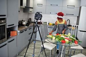 mulher afro-americana filmando sua transmissão de blog sobre comida saudável na cozinha de casa. foto