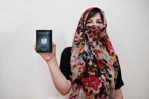 jovem muçulmana árabe em roupas hijab segura passaporte da república árabe do egito no fundo da parede branca, retrato de estúdio. foto