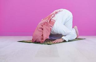 jovem muçulmano árabe rezando no chão em casa foto