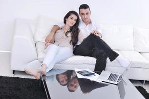 casal alegre relaxa e trabalha no computador portátil em casa moderna foto