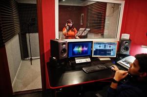 jovem cantora asiática com música de gravação de microfone em estúdio de música com produtor de som. foto