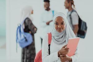 aluna africana com grupo de amigos em segundo plano vestindo roupas tradicionais de hijab islâmico. foco seletivo foto