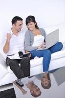 casal alegre relaxa e trabalha no computador portátil em casa moderna foto