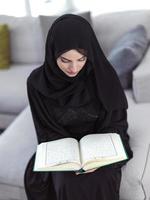 jovem muçulmana lendo o Alcorão em casa foto