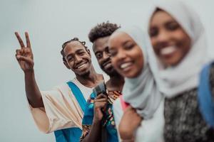 grupo de estudantes africanos felizes conversando e reunião de equipe trabalhando juntos em meninas de lição de casa vestindo moda hijab muçulmana do sudão traidiional foto