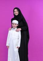 retrato de mãe muçulmana e filho em fundo rosa foto