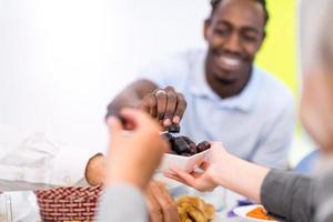 família muçulmana multiétnica moderna compartilhando uma tigela de datas foto