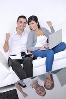 casal alegre relaxa e trabalha no computador portátil em casa moderna foto