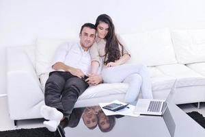 casal alegre relaxa e trabalha no computador portátil em casa moderna foto