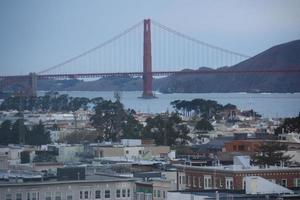 tirada ao pôr do sol, a ponte golden gate e edifícios de sanfransisco. foto