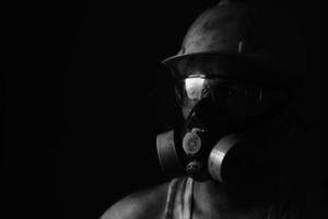mineiro de retrato em capacete, respirador e óculos olhando para light.dirty trabalhador em foto preto e branco.