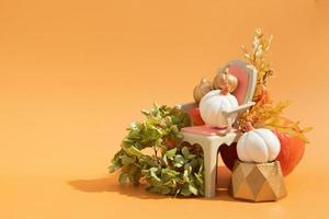 composição criativa de natureza morta de outono. abóboras decorativas douradas e brancas com cadeira e flores secas foto