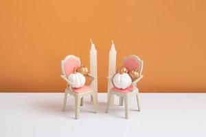 composição criativa de uma natureza morta de outono. abóboras decorativas douradas e brancas em uma cadeira com velas