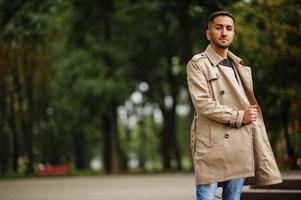 homem elegante kuwaitiano em trench coat andando no parque. foto