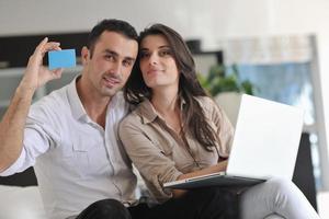 casal alegre relaxa e trabalha no computador portátil em casa moderna foto