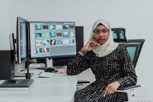 jovem empresária muçulmana moderna afro-americana usando um cachecol em um local de trabalho de escritório brilhante criativo com uma tela grande. foto