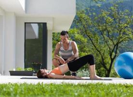 mulher com personal trainer fazendo exercícios de ioga matinais foto