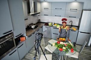 mulher afro-americana filmando sua transmissão de blog sobre comida saudável na cozinha de casa. ela segura um repolho. foto