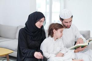 família muçulmana lendo o Alcorão e orando em casa foto