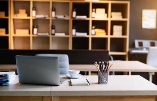 computador portátil de espaço de trabalho, tablet, lápis e xícara de café com vaso de plantas na mesa de escritório. foto