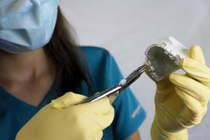 a mulher dentista está segurando dentaduras nas mãos e instrumentos foto