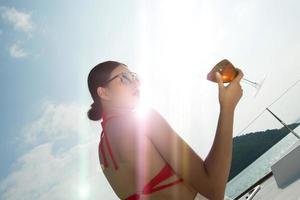 linda mulher de pele bronzeada de raça mista asiática anda ao longo de iates de luxo no oceano profundo, garota de óculos de sol de biquíni vermelho posando como modelo no cais de ancoragem sob o céu azul de verão nas férias
