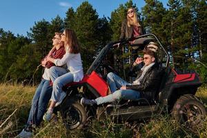 grupo jovens felizes desfrutando de um belo dia de sol enquanto dirigia um carro de buggy off road foto