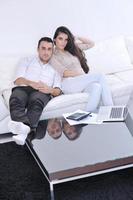 casal alegre relaxa e trabalha no computador portátil em casa moderna foto