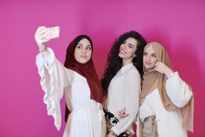 mulheres muçulmanas tirando foto de selfie isoladas em rosa