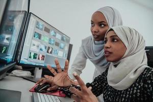 amigos no escritório duas jovens empresárias muçulmanas modernas americanas usando cachecol no local de trabalho de escritório brilhante criativo com uma tela grande foto