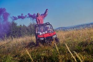 pessoas animadas se divertindo aproveitando um belo dia ensolarado segurando tochas coloridas enquanto dirigia um carro de buggy off road foto