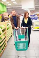 casal feliz com carrinho de compras vazio foto