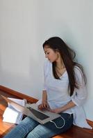 jovem relaxada em casa trabalhando no computador portátil foto