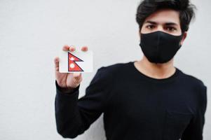 homem asiático usar todo preto com máscara facial segurar a bandeira do nepal na mão isolada no fundo branco. conceito de país coronavírus. foto