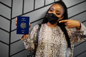 mulher africana usando máscara facial preta mostra passaporte do Sudão do Sul na mão. coronavírus no país africano, fechamento e quarentena de fronteiras, conceito de surto de vírus. foto